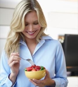 Young lady eating Yoghourt with Fruits